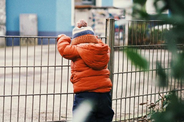 A small child standing next to a fence